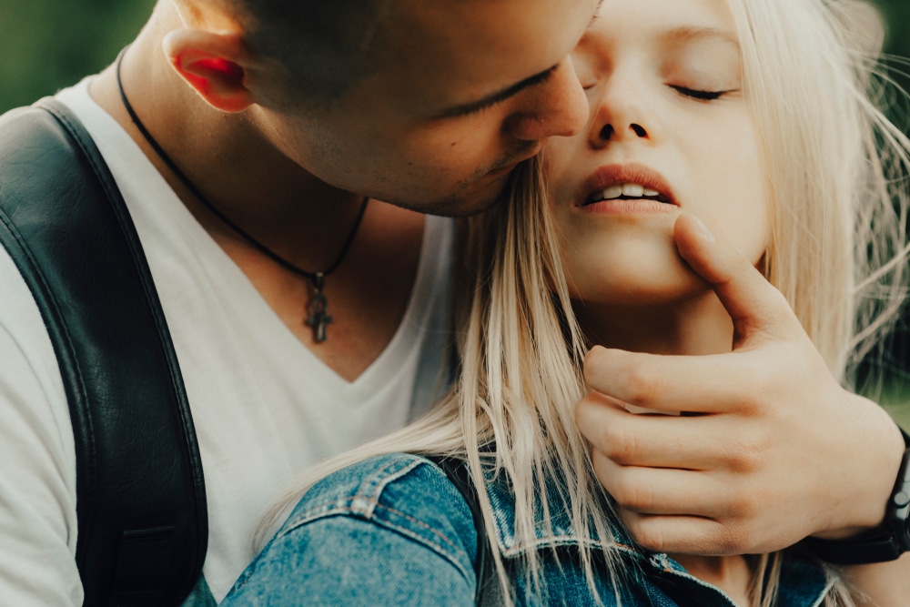 Handsome young man embracing young woman and touching her face affectionately while standing in nature - The Libra Man with Leo Rising