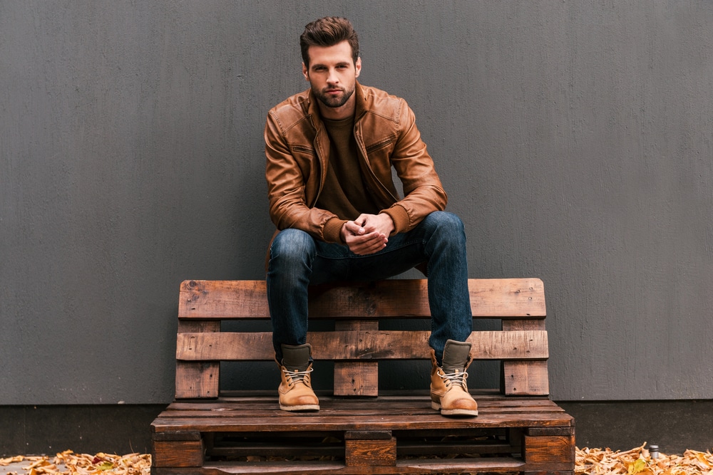 Handsome young man sitting on the wooden pallet and looking at camera - The Libra man wirh Scorpio Rising