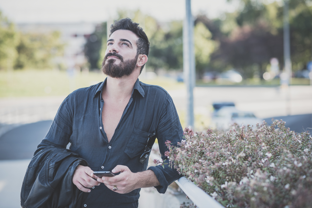 young handsome attractive bearded model man using smartphone in urban context - The Libra Man with Virgo Rising
